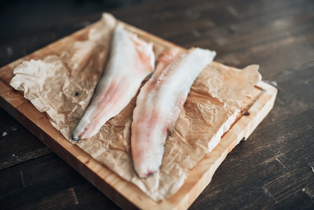 Raw fish slices, knife on cutting board, top view