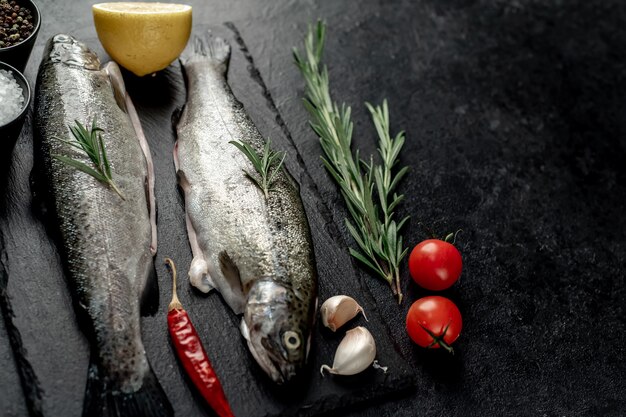 Trota di pesce crudo con spezie pronte per la cottura su uno sfondo di pietra