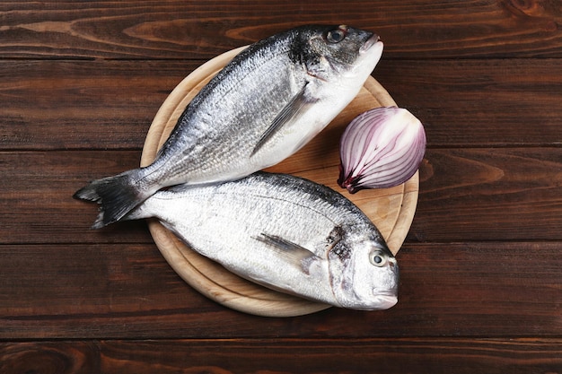 Raw fish with onion on cutting board