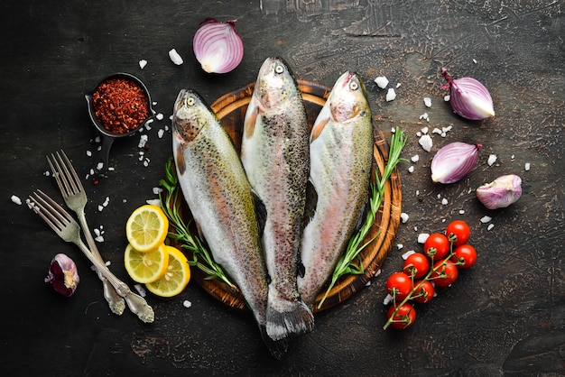 Raw fish with vegetables on a black wooden background Fish trout Top view Free space for your text