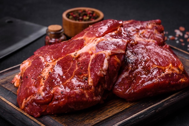 Raw flank beef steak and ingredients for cooking on a wooden board close up