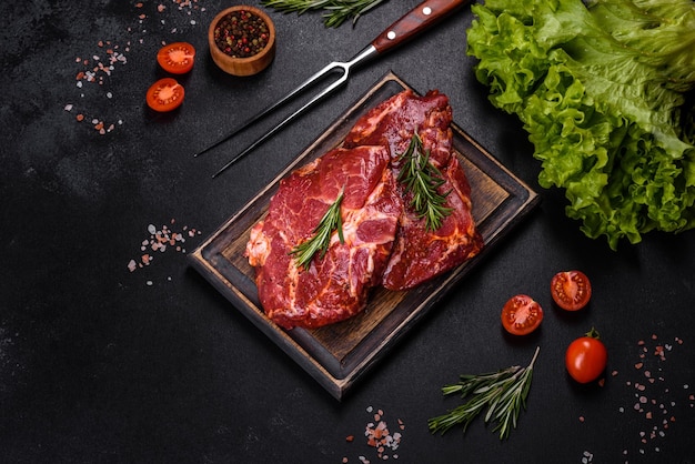 Raw flank beef steak and ingredients for cooking on a wooden board close up