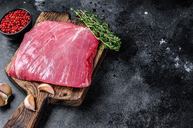 Raw flank or flap beef meat steak on a wooden cutting board