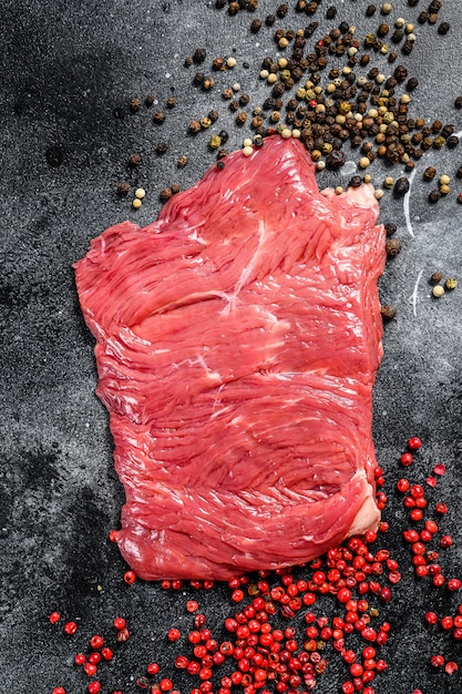 Raw Flank steak met zwarte en roze peper. Bovenaanzicht