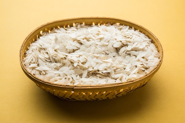 Raw Flattened Rice or Thick or thin Rice Flakes for Namkeen Chivda snacks or Aloo Poha for Indian Breakfast, served in a bowl