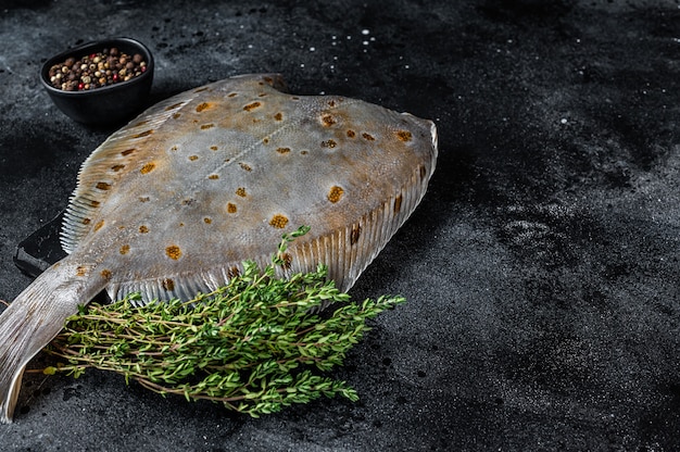 Raw flounder flatfish fish on marble board with thyme