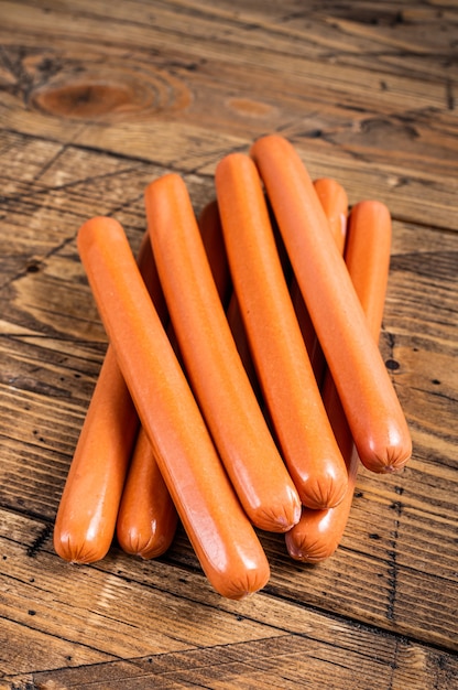 Raw frankfurter sausages on kitchen table. Wooden background. Top view.