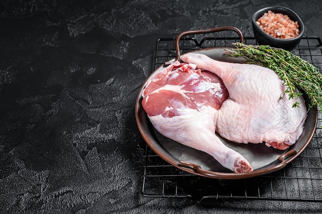 Raw Free range duck legs in a steel tray with thyme Black background Top view Copy space