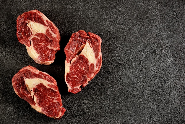 Raw fresh beef steaks on a black background