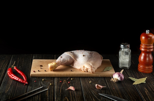 Photo raw fresh chicken leg or drumstick on cutting board with dark advertising space