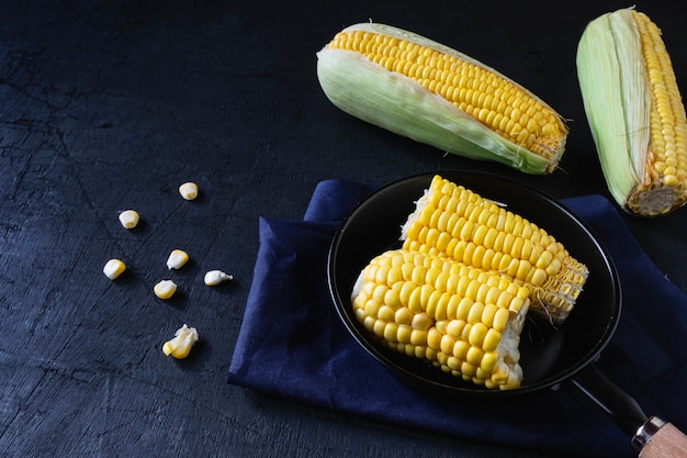 Raw Fresh corn in pan on black background