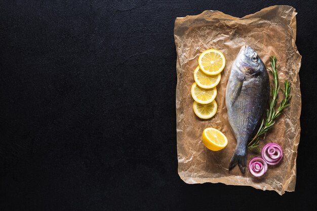 Raw Fresh Dorado Fish on cooking paper prepared for cooking with spices on a black background. Seafood. Top view. Copy space.