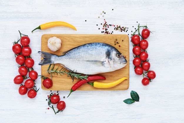 Pesce crudo fresco di dorado con verdure e spezie. concetto di cibo sano. vista dall'alto, copia dello spazio. concetto di pesce mediterraneo.