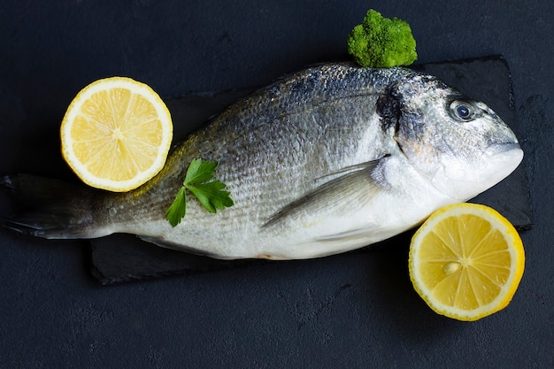 Raw, fresh fish, trout, on a cutting board, with chopped lemon and herbs