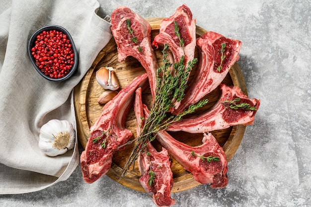 Raw fresh lamb rib chops with salt, pepper and herbs.