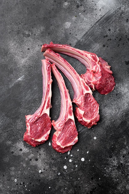 Raw fresh lamb ribs set on black dark stone table background top view flat lay with copy space