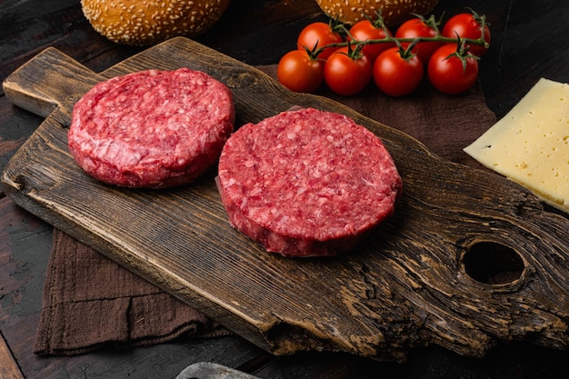 Hamburger di manzo grande fresco crudo sul vecchio fondo della tavola di legno scuro