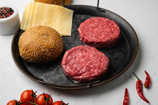 Raw fresh large beef burger on white stone table background