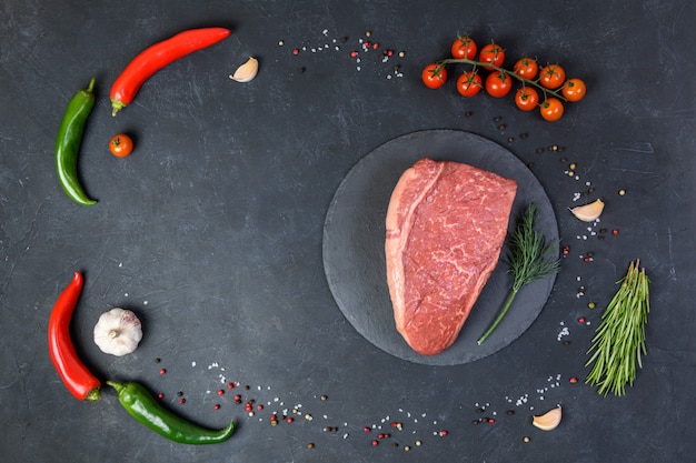 Raw fresh marbled meat and seasonings on dark background top vie