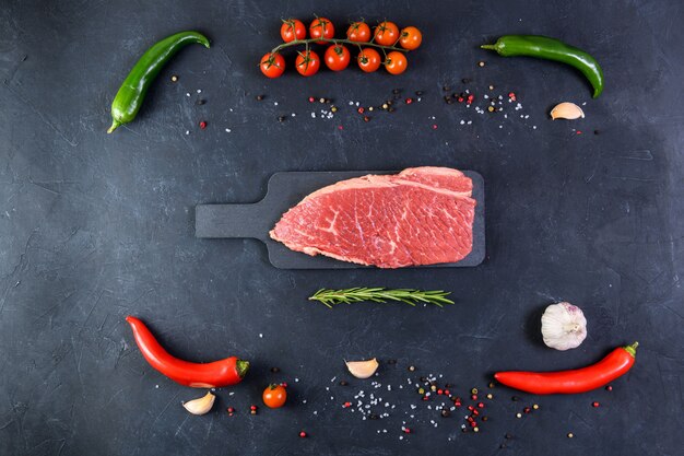 Raw fresh marbled meat and seasonings on dark background top vie