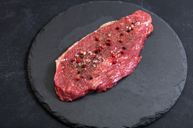 Raw fresh marbled meat and seasonings on dark ckground top vie