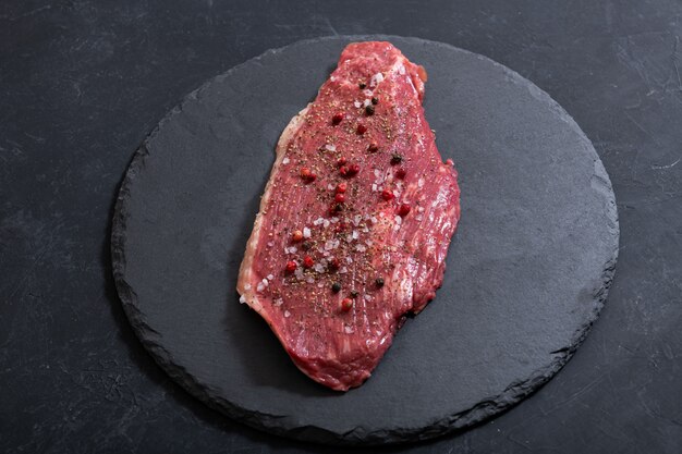 Raw fresh marbled meat and seasonings on dark ckground top vie