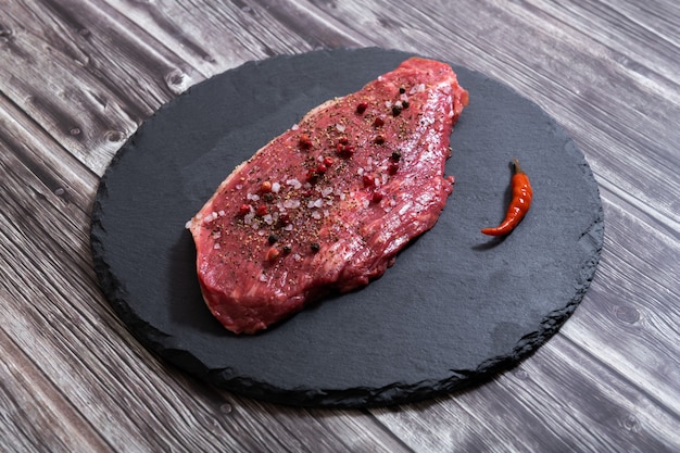 Raw fresh marbled meat and seasonings on dark ckground top vie