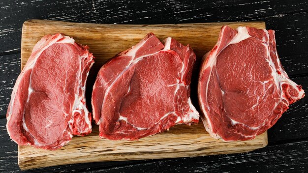 黒の背景の上面図に生の新鮮な肉のビーフステーキ