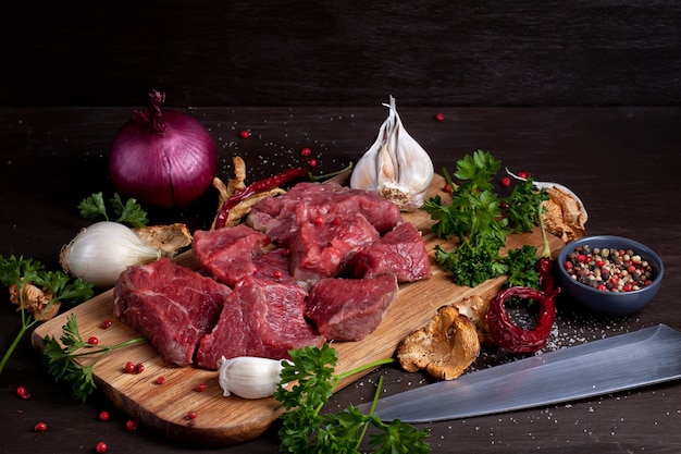 Raw fresh meat; bottle of wine and seasonal autumn organic vegetables on wooden board ready for cooking