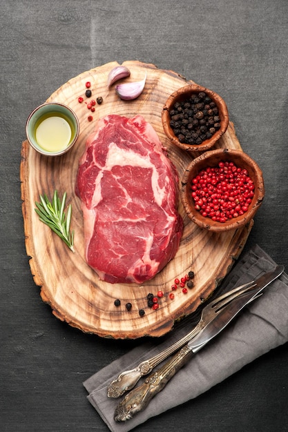 Raw fresh meat Ribeye steak entrecote and seasoning on wooden board