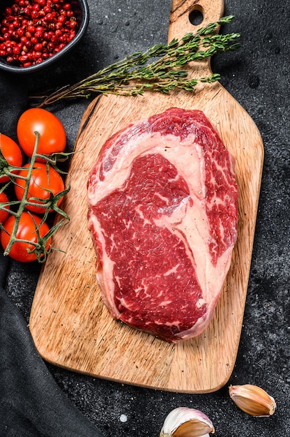 커팅 보드에 조미료와 신선한 생고기 Ribeye 스테이크. 등심 비프 스테이크