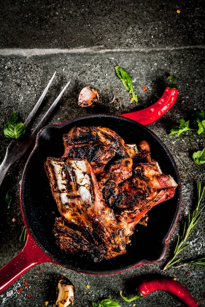 Raw fresh meat, roasted or grilled lamb or beef ribs with red tomato sauce, hot pepper, garlic and spices in skillet 