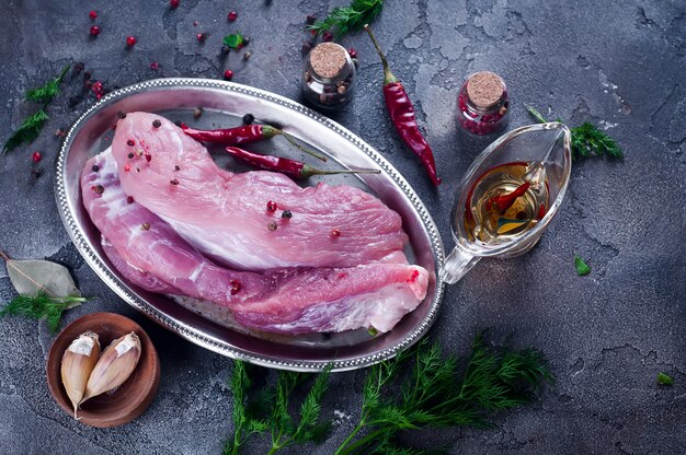 Raw fresh meat steak entrecote and seasonings in the iron plate with oil, chili, spices dill