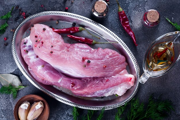 Entrecote e condimenti di bistecca di carne fresca cruda nel piatto di ferro con olio, peperoncino rosso, spezie aneto