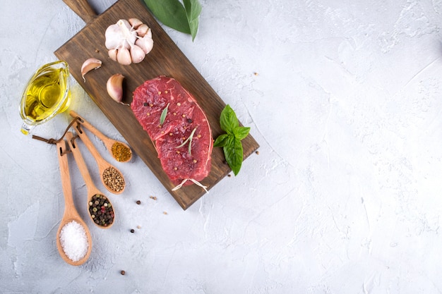 Raw fresh meat steak and seasoning spices  on a gray concrete background Top view. Copy space.