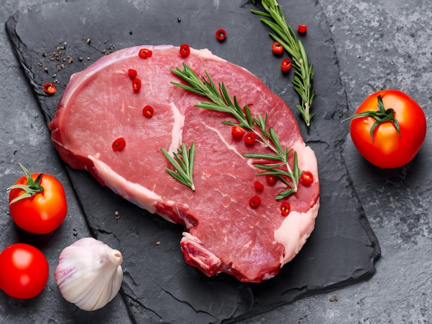 Raw fresh meat steak with cherry tomatoes hot pepper garlic oil and herbs