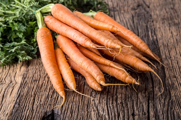 Raw fresh organic carrots on rustic oak table