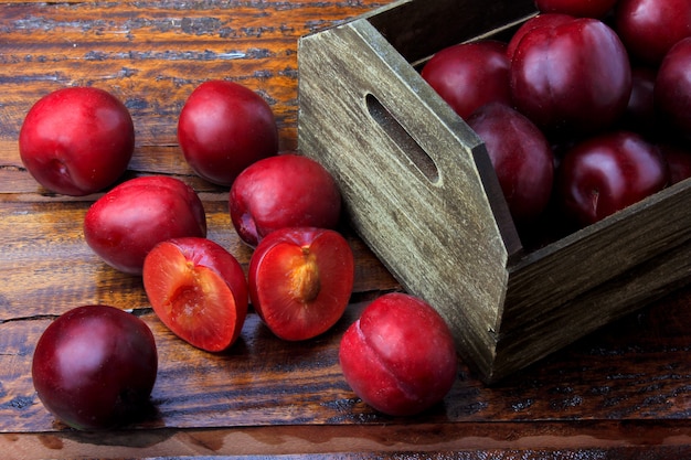 Raw and fresh organic plums inside rustic fabric wooden box on rustic table