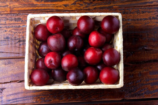 Raw and fresh organic plums inside rustic fabric wooden box on rustic table