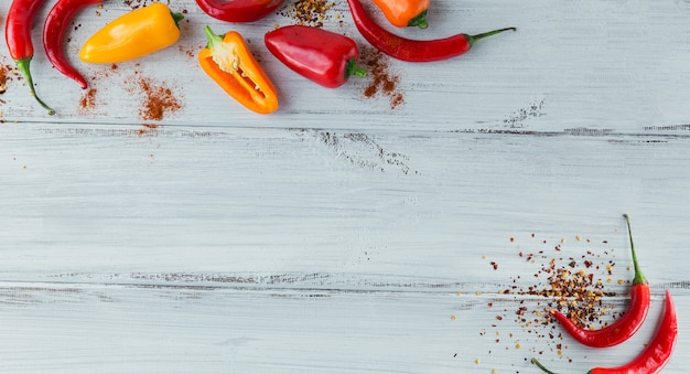 Raw fresh organic red chili pepper and assorted spices on white wooden surface