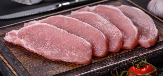 Raw fresh pork meat sliced on a wooden cutting board