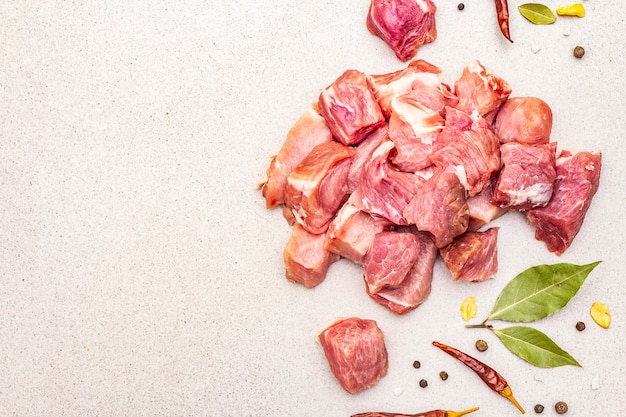 Foto spalla di maiale fresca cruda, tagliata a pezzi con spezie