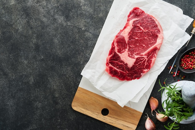 원시 신선한 ribeye 스테이크 또는 Ribeye 스테이크 원시 신선한 대리석 고기 Ribeye 블랙 앵거스 및 조미료 후추 로즈마리 백리향 및 오래 된 나무 소박한 배경에 소금 상위 보기 및 복사 공간