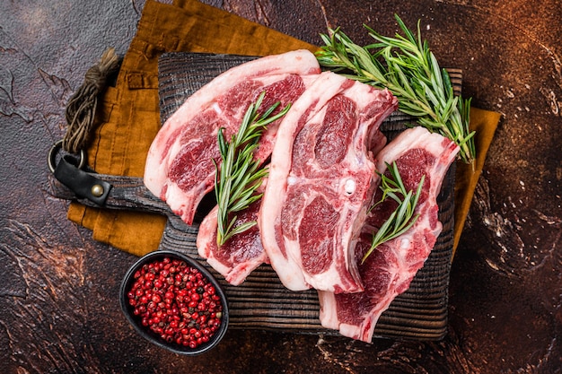 Raw fresh saddle of lamb mutton with herbs and spices on butcher board Dark background Top view