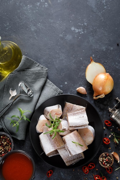 Raw fresh sliced hake fish with ingredients for cooking