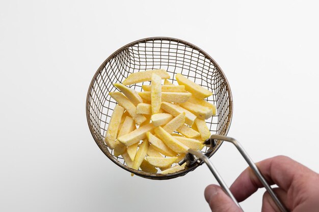Raw fries in a fryer sieve making French fries