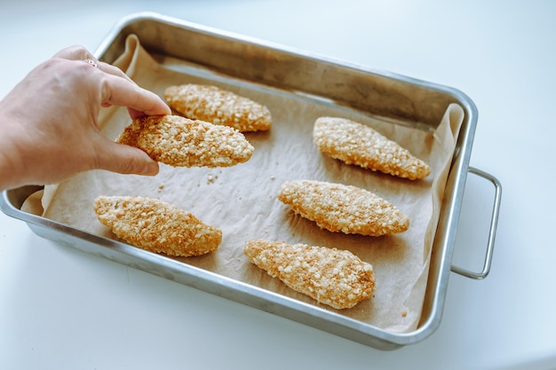 Photo raw frozen breaded chicken pieces on a baking sheet