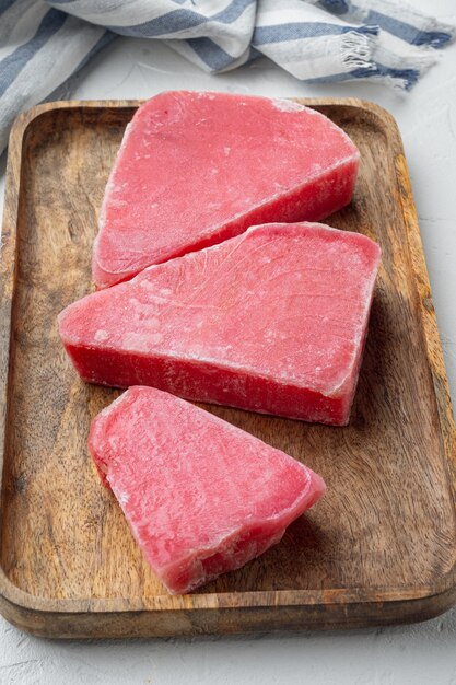 Raw frozen tuna fish fillet set, on wooden tray, on white stone  background