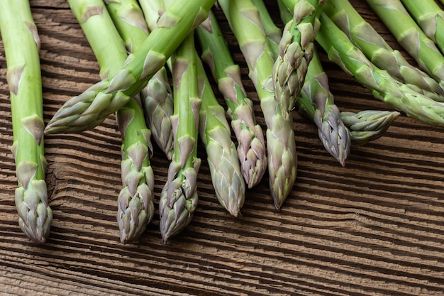 Raw garden asparagus stems fresh green spring vegetables on wooden background