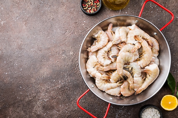 Raw giant shrimps with lemon and spices in a frying pan